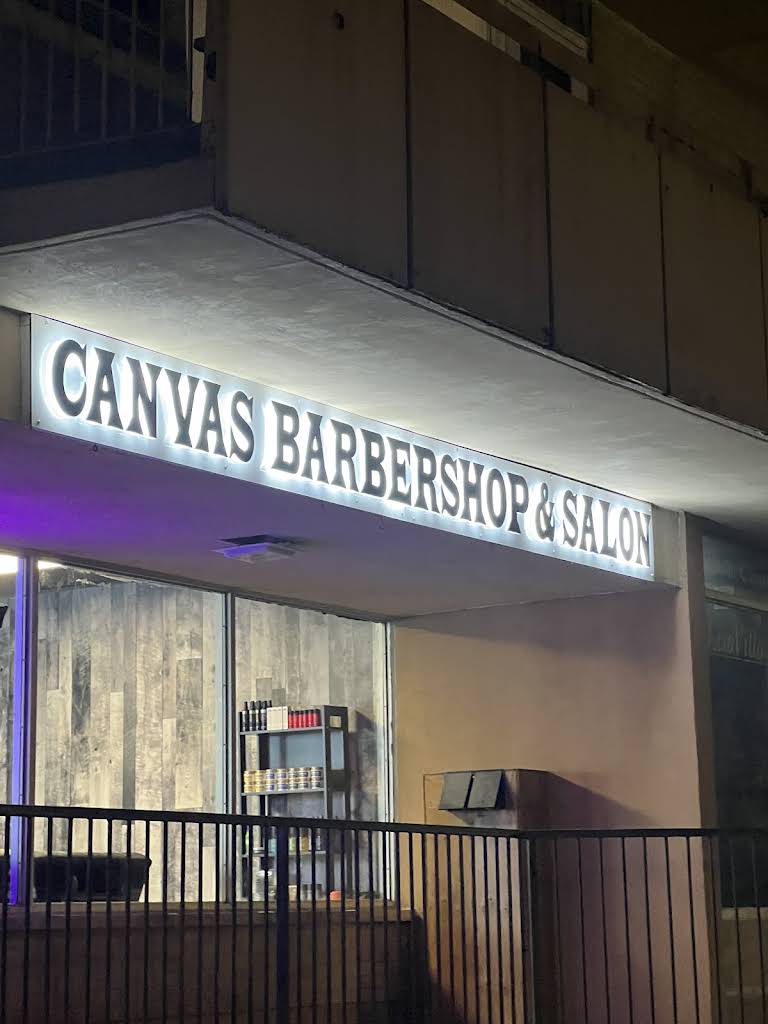 The illuminated Canvas Barbershop and Salon sign